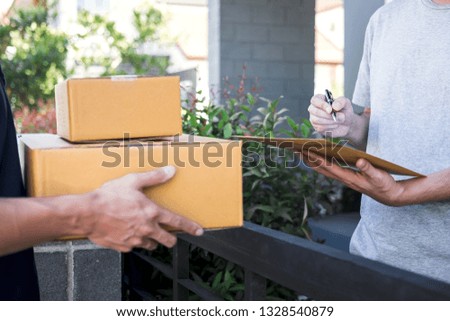 Delivery mail man giving parcel box to recipient, Young man signing receipt of delivery package from post shipment courier at home.