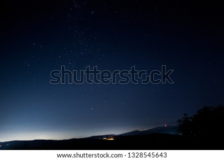 Starry night on the farm with mountains in the background