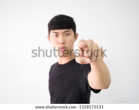 Young Asian man black shirt point left finger hand at you blur serious at face looking camera white isolated background concept