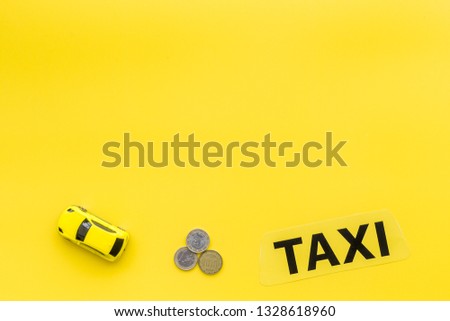 Taxi operator concept. Chip service. Sign taxi ner car toy and coins on yellow background top view copy space