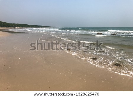 Pictures of the sandy beach and the sea on a clear day under the blue sky, with scattered small rock on the coast line, have wave all the time, Phetchaburi, the lower central of Thailand.