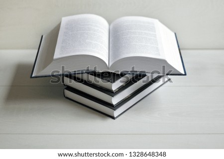 Books and an open book on a light wooden background.