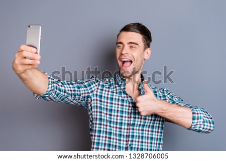 Close up photo attractive amazing he him his man arms hands new telephone smart phone make take selfies thumb up advice recommend wearing casual plaid checkered shirt outfit isolated grey background