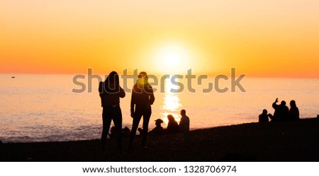 Silhouetts of people taking photos and having fun in the sunset - travel photography
