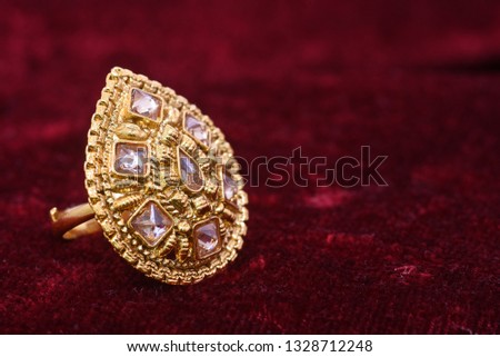 Fancy designer precious jewelry golden ring closeup macro image on red background for woman