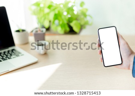 Mockup image man hand holding texting using black mobile,cell phone at desk with copy space,white blank screen for text.concept for contact business,people communication,design creative work