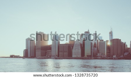 World famous New York Financial District and the Lower Manhattan at dawn viewed from the Brooklyn Bridge Park. Low contrast color image.