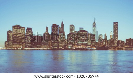 Panoramic view of New York Financial District and the Lower Manhattan at night viewed from the Brooklyn Bridge Park. Low contrast color image.