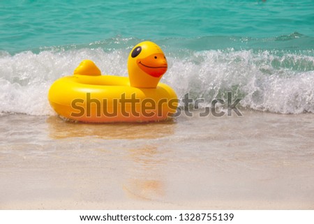 Inflatable ring player with soft wave of blue ocean on sandy beach. Background of travel in summer season