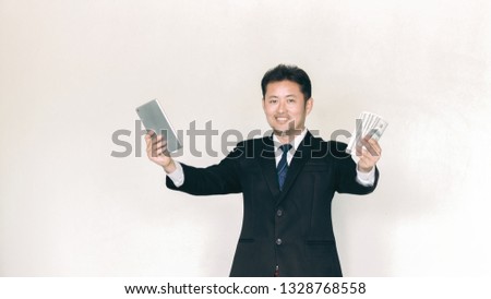 Casually dressed bearded businessman holding wad of cash and smart phone in hands