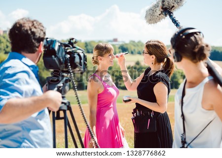 Model in the make-up during video shoot on production set with camera and sound engineer on stand-by