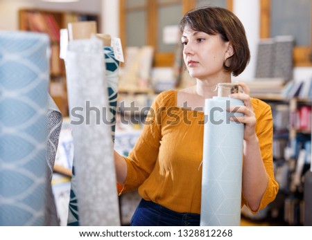 Female seller organizing assortment of textile on shelves in fabric store

