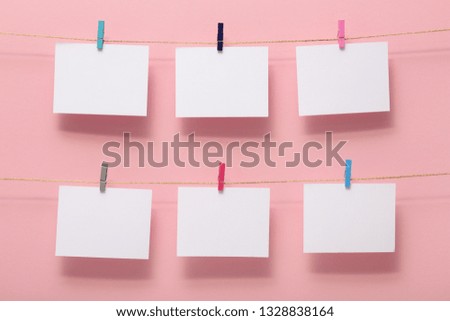place for photo cards of  moments of life, empty blanks attached to a linen rope in two rows withstationery clips on pastel pink background, a concept template for text, images, idea for home decor