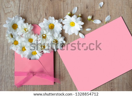 Beautiful Spring flowers in envelope. Chamomile on a wooden background. Pink Letter mockup with a free space. Greeting card for Happy Easter,  mother's day, International Women Day. Letter of love.