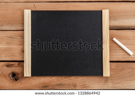 Black Board in wooden frame on wooden background with chalk