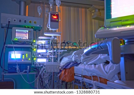Glowing monitors in intensive care department. Nigth shift at icu, patient in critical state. Royalty-Free Stock Photo #1328880731