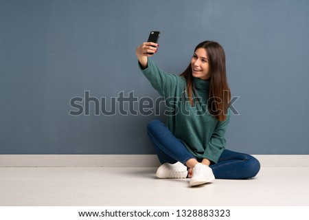 Young woman sitting on the floor making a selfie