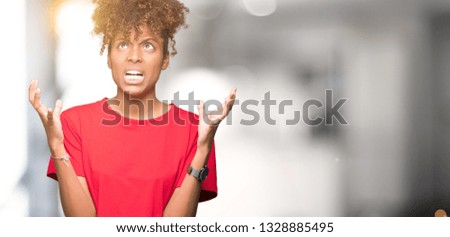 Beautiful young african american woman over isolated background crazy and mad shouting and yelling with aggressive expression and arms raised. Frustration concept.