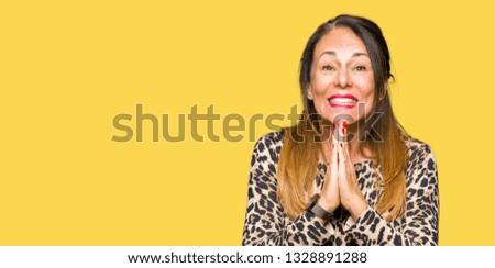 Beautiful middle age woman wearing leopard animal print dress praying with hands together asking for forgiveness smiling confident.