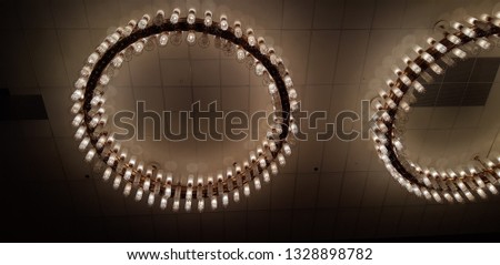 Picture taken from the phone.Round chandelier with a bunch of ceiling lamps on a dark ceiling.