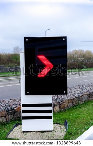 Electronic scoreboard with red arrow pointer on gas station. Digital display on city street