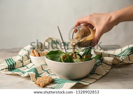 Pouring of tasty tahini from jar onto fresh vegetables in bowl Royalty-Free Stock Photo #1328902853