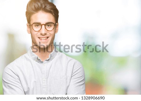 Young handsome man wearing glasses over isolated background Smiling with hands palms together receiving or giving gesture. Hold and protection