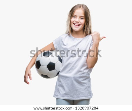 Young beautiful girl holding soccer football ball over isolated background pointing and showing with thumb up to the side with happy face smiling