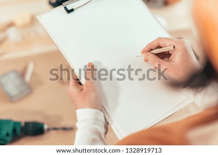 Female carpenter writing DIY project notes on clipboard note pad, mock up image