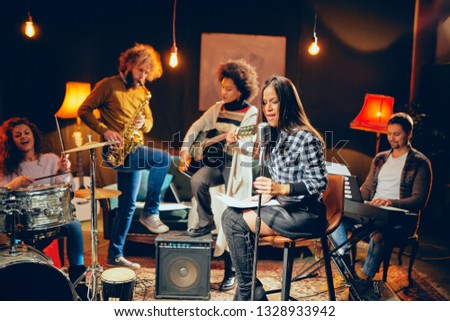 Band practice in home studio. Woman singing while rest of the band playing instruments.