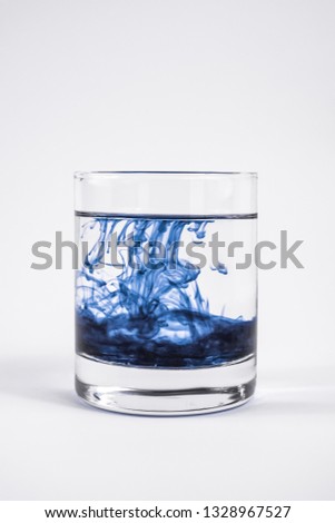 Water contamination concept. Dark substance dissolving with clean water in a glass in white background