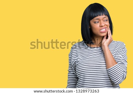 Beautiful young african american woman wearing stripes sweater over isolated background touching mouth with hand with painful expression because of toothache or dental illness on teeth. Dentist