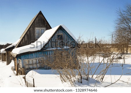 Crooked wooden house in an abandoned garden. Winter
