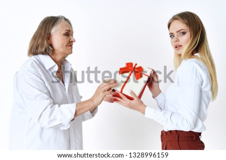An elderly grandmother gives a young woman a gift box           