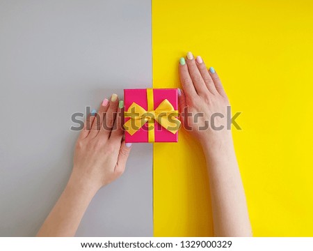 women's hands, gift box on a color paper background