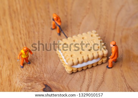 Miniature people move biscuit, cooking and decoration concept. The concept of a collective solution to any problem. Close-up view.