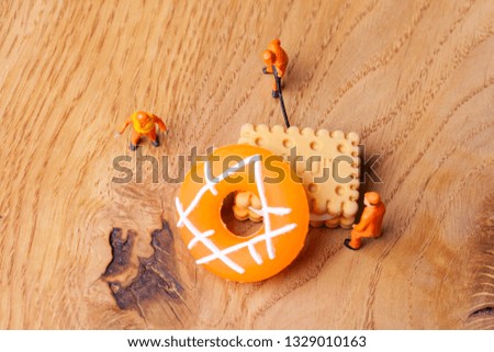 Miniature people move biscuit, cooking and decoration concept. The concept of a collective solution to any problem. Close-up view.
