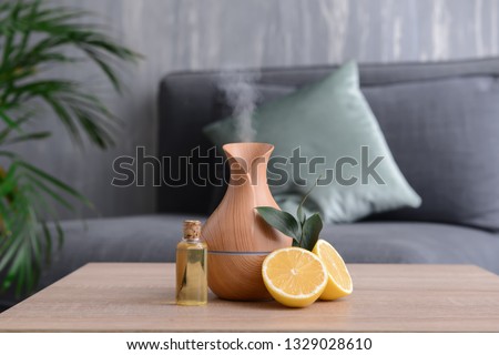 Aroma oil diffuser and citrus fruit on table in room Royalty-Free Stock Photo #1329028610