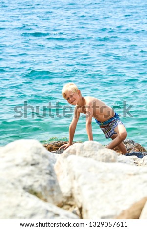 Child boy balancing on stones on the shore of the lake Garda, Italy