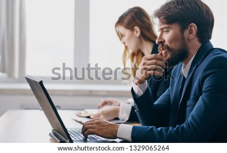 A man sits in front of a laptop next to a woman Work discussion