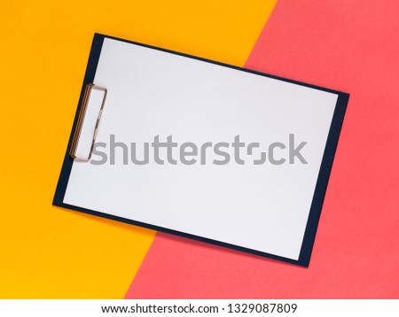 Creative geometric flat lay background. Blank clip board, yellow and pink color paper. Minimalistic design concept