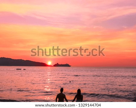 pair of lovers stand on the seashore at sunset and hold hands