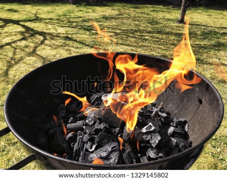 Round Barbecue with burning coal and fire in the garden