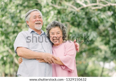Happy Asian senior couple laughing and smiling while holding each other outdoor in the park. Royalty-Free Stock Photo #1329150632