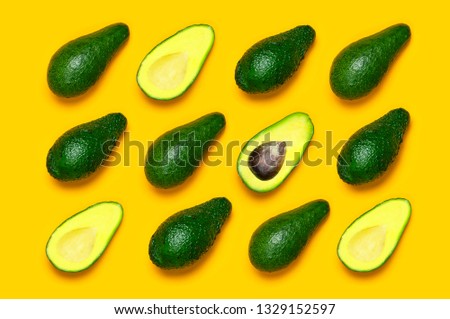 Ripe sliced avocado pattern on yellow background top view. Creative food composition Flat lay. Pop art design, tropical summer abstract background with avocado. Green avocadoes pattern. 