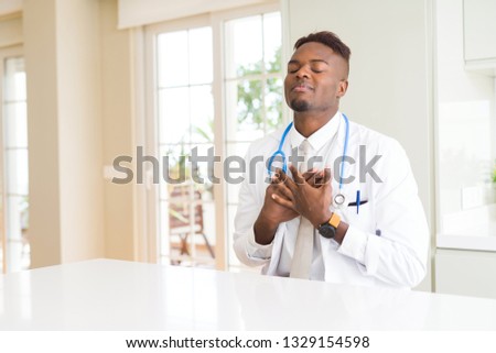 African american doctor man at the clinic smiling with hands on chest with closed eyes and grateful gesture on face. Health concept.