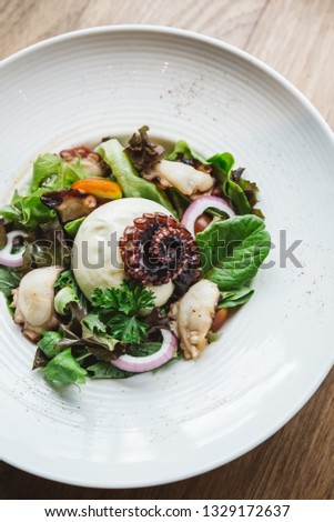 Top view of Smoked Galician Octopus with Burrata Cheese, radish, green oak and tomato.