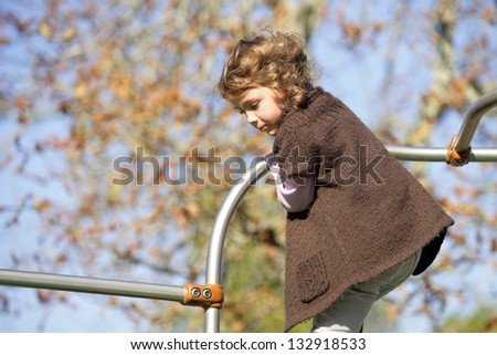 Little girl playing on climbing frame