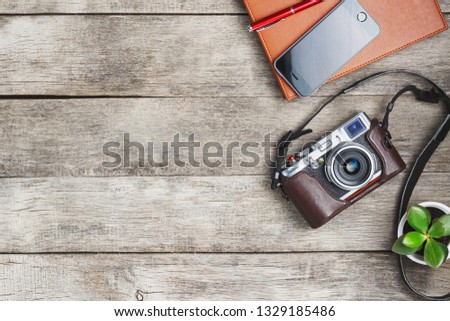 Classic camera with a brown organizer red pen on a gray wooden, vintage desk with a telephone and green growth. The concept of the list for the photographer in travels. Free space in country style