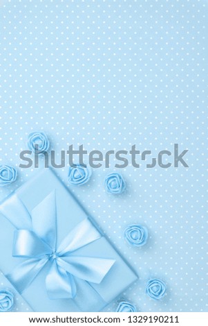 Springtime decorated blue gift box and rose flowers top view for 8 March Women day copy space on pastel blue paper background. Mother day template with present box. Flat lay. Springtime collection.